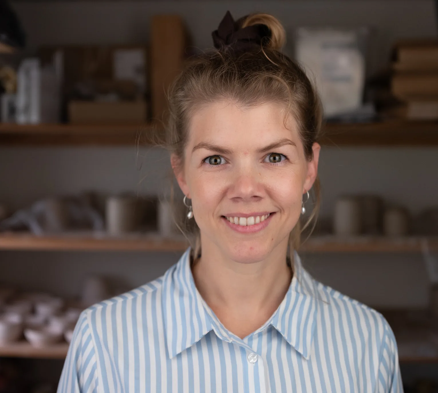 Heidi i værkstedet foran hylderne med kopper